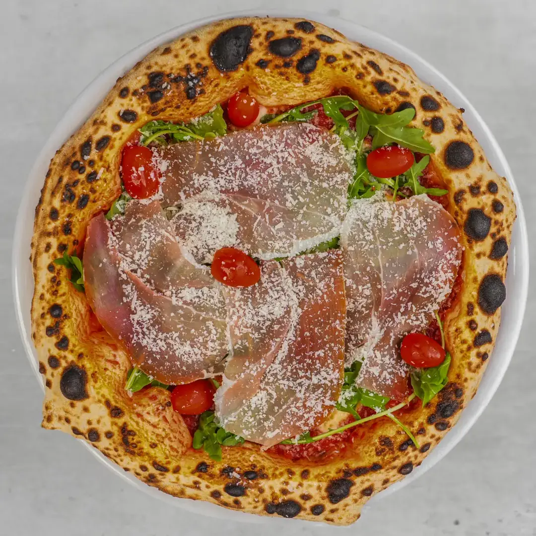 Pizza neapolitańska z prosciutto crudo, rukolą i pomidorkami cherry z Pizzerii Czerwony Stefan — dostawa dla firm Warszawa
